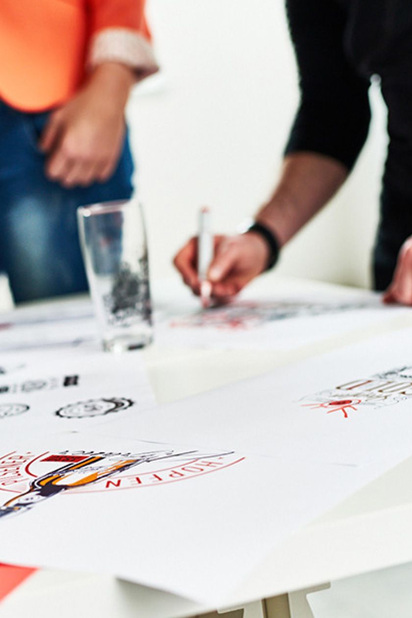 Design teaser: Persone che creano loghi e illustrazioni su carta. Team di design al lavoro.